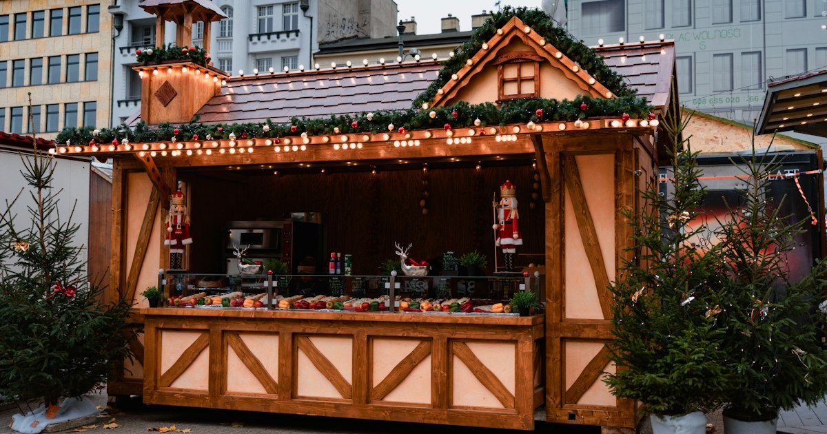 A wooden Christmas market hut decorated with garlands, fairy lights and two toy nutcrackers.