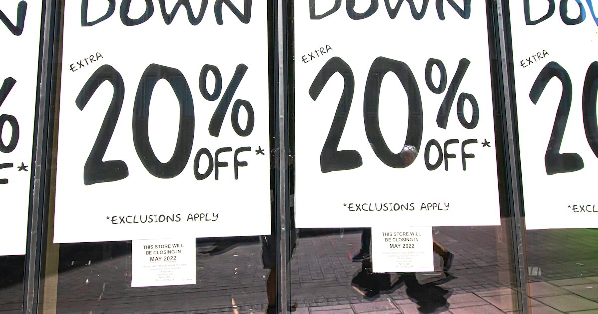 Identical hand-lettered CLOSING DOWN sale posters repeated across the windows of a shop at night.