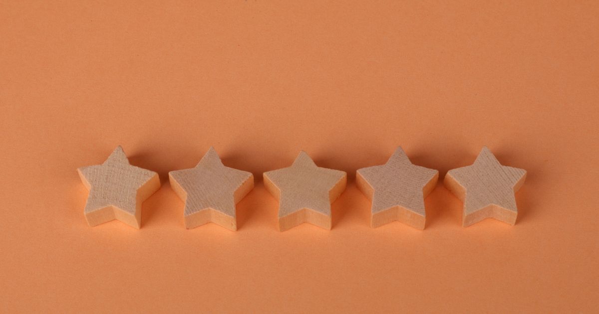 Five plain wooden star shapes lined up in a row on a terracotta background.
