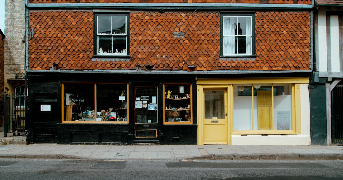 Two small independent shopfronts on a high street, each with a step up to the door.