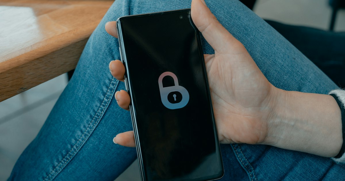A hand holding a smartphone whose screen shows only a padlock symbol